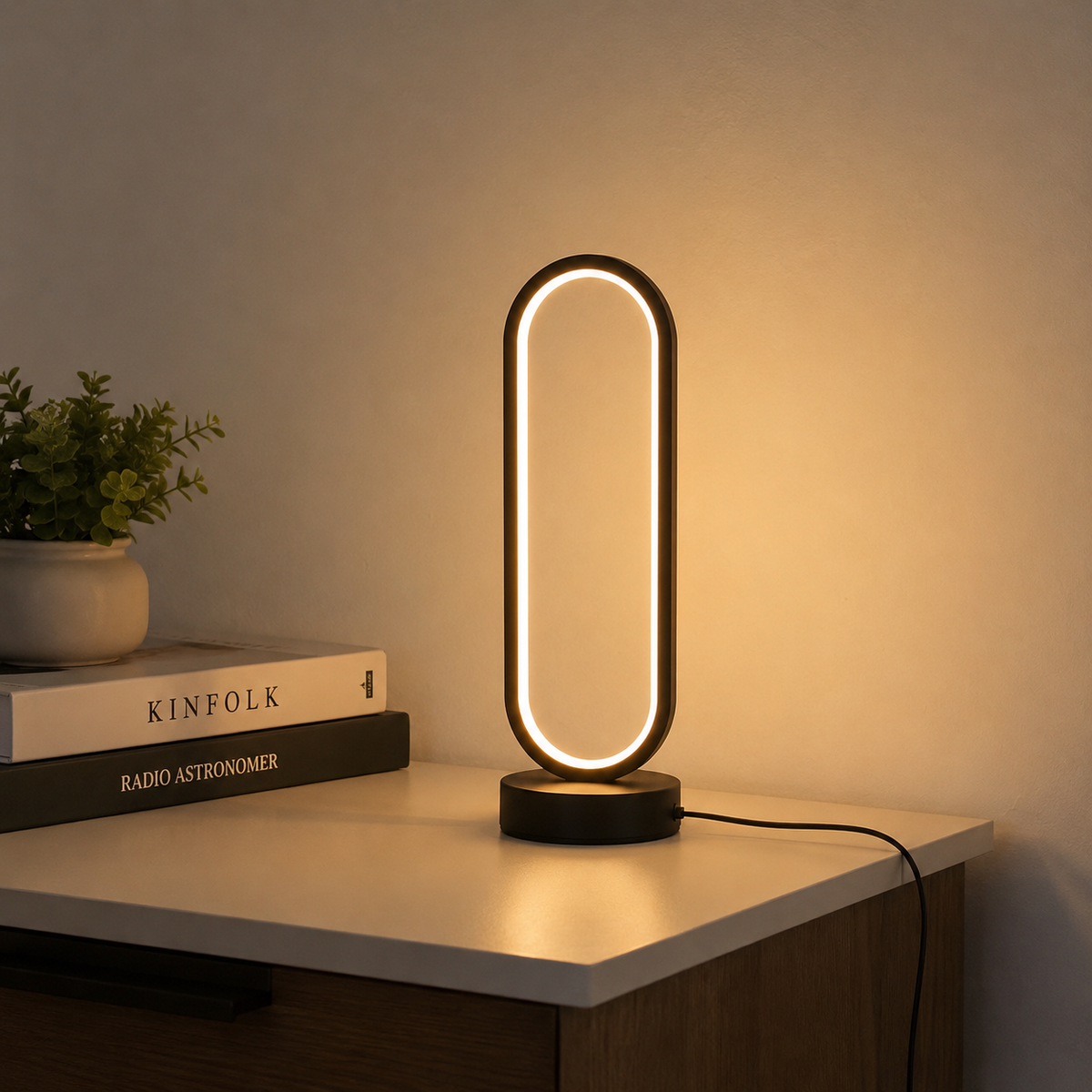Ring Table Lamp lit on a side table beside books